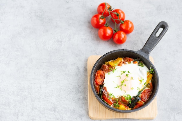 Uovo al forno in padella cosparso di crescione Shakshuka con pomodori peperoni spinaci