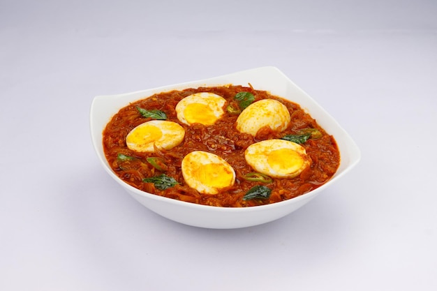 Uovo arrosto o uovo indiano masala curry arrosto di uovo rosso piccante disposto in una ciotola di ceramica bianca