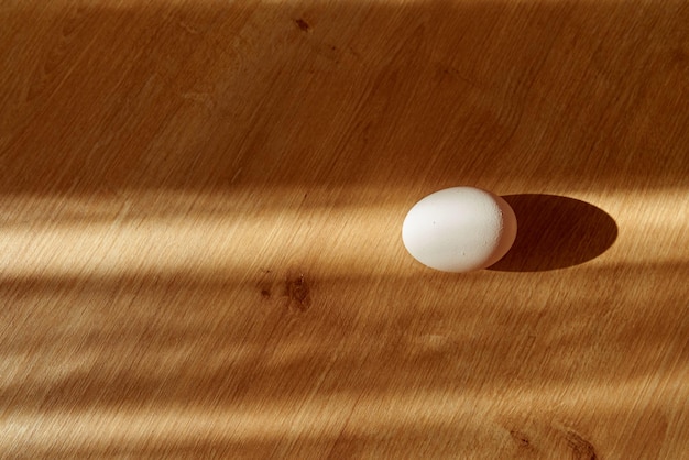 Uovo bianco biologico fresco su un bancone da cucina in legno alla luce del giorno.