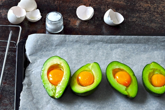 Uovo crudo in avocado su una teglia. Cucinare l'avocado con l'uovo. Ricetta del pranzo di Keto.