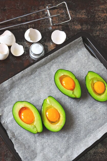 Uovo crudo in avocado su una teglia. Cucinare l'avocado con l'uovo. Ricetta del pranzo di Keto.