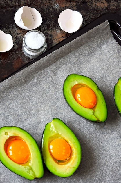 Uovo crudo in avocado su una teglia. Cucinare l'avocado con l'uovo. Ricetta del pranzo di Keto.