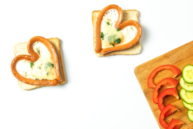 Uovo di gallina in una salsiccia a forma di cuore, in padella con pane tostato, isolato, vista dall'alto