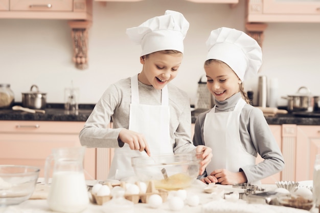 Uovo di miscelazione felice della ragazza e del ragazzo che cucina alla cucina.