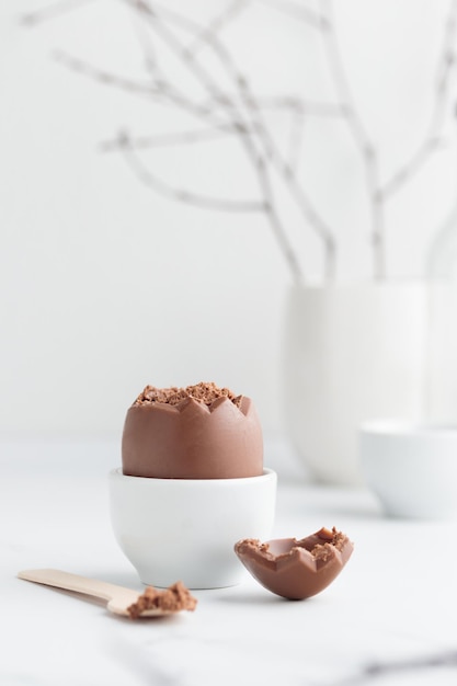 Uovo di Pasqua al cioccolato in un portauovo bianco