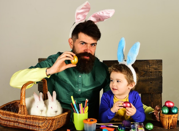 Uovo di Pasqua che decora padre e figlio che dipingono le uova per la vacanza in famiglia felice nelle orecchie del coniglietto