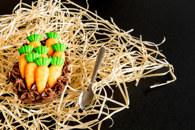 Uovo di Pasqua con la carota decorativa sul concetto di pasqua del fondo nero