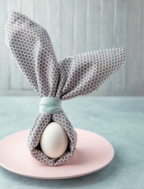 Uovo di Pasqua decorato con tovagliolo a forma di orecchie di coniglio.