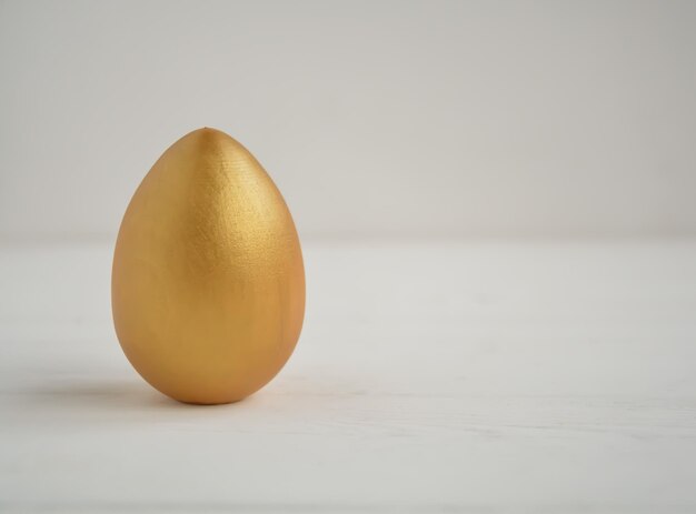 Uovo di Pasqua di colore oro di Pasqua su sfondo bianco con spazio per il testo