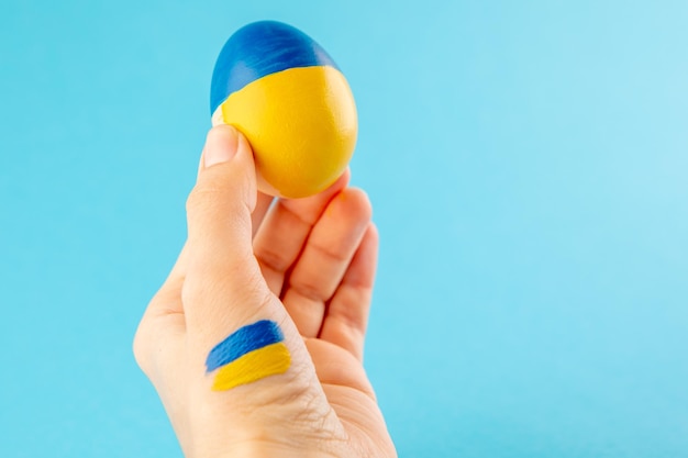 Uovo di Pasqua in mano di donna sui colori della bandiera dell'ucraina come concetto per la guerra in ucraina