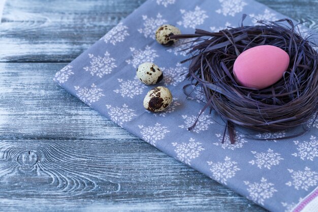 Uovo di Pasqua in un nido, tovagliolo su un legno.