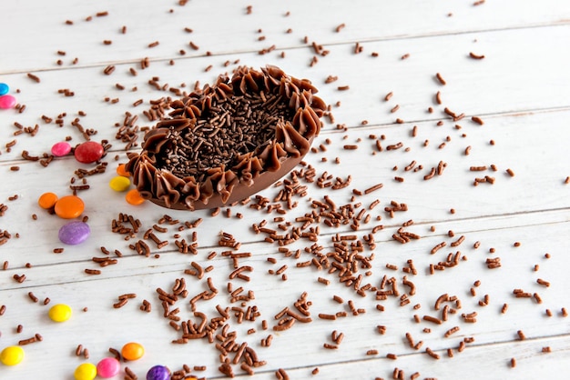 Uovo di Pasqua ripieno di cioccolato su sfondo pasquale con granuli di brigadeiro