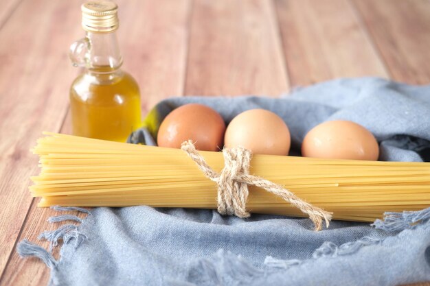 Uovo di spaghetti lunghi gialli e olio sulla tavola