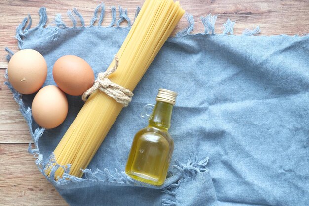 Uovo di spaghetti lunghi gialli e olio sulla tavola