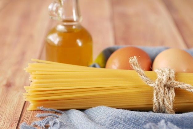 Uovo di spaghetti lunghi gialli e olio sulla tavola