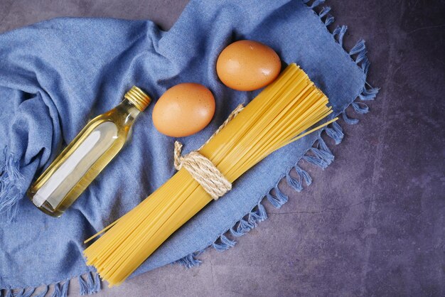 Uovo di spaghetti lunghi gialli e olio sulla tavola