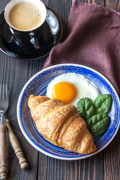 Uovo fritto con cornetto e una tazza di caffè