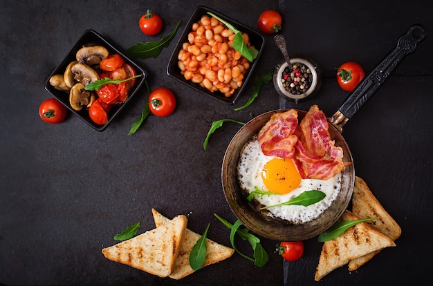 uovo fritto, fagioli, pomodori, funghi, pancetta e toast.