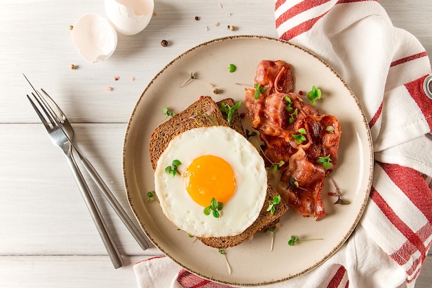 Uovo fritto per la colazione con pancetta microgreen su sfondo chiaro nessun fuoco selettivo delle persone