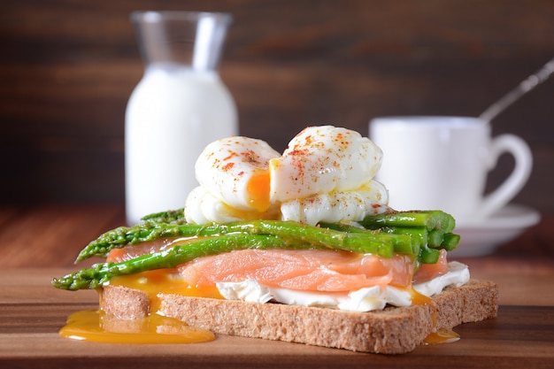 Uovo in camicia con asparagi fritti, crema di formaggio, salmone e spezie su un toast. Concetto di colazione francese sana