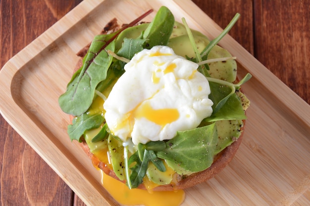 Uovo in camicia con avocado e rucola su un toast