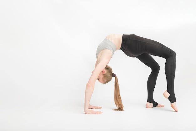 Urdhva Dhanurasana Upward Bow Wheel Pose Girl è ginnasta durante l'allenamento su sfondo bianco L'allenatore di yoga esegue asana Bella giovane donna allena la flessibilità