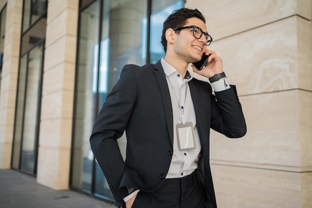 Usa il telefono nelle sue mani per comunicare con il cliente Un uomo d'affari va in ufficio