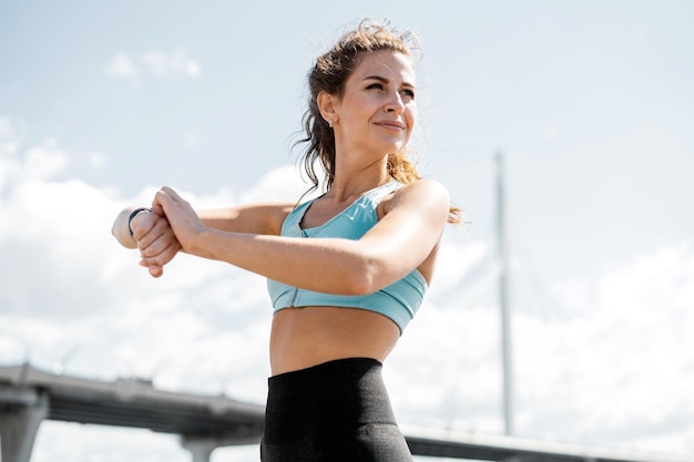 Usa un orologio sulla sua mano per allenare una donna sportiva che fa esercizi di fitness per strada