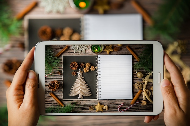 Usando la compressa della tenuta della mano scatta la foto Carta della cornice di Natale di festa