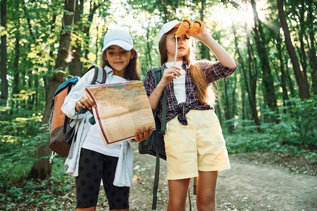 Usando la mappa Due ragazze sono nella foresta con un'attività di svago alla scoperta di nuovi posti