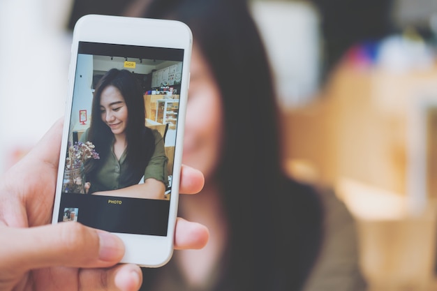 Usando lo smartphone scattare una foto di una donna