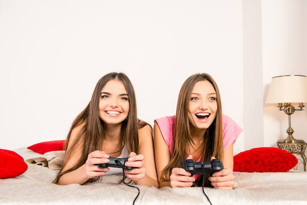 Uscite ragazze sexy che giocano ai videogiochi in camera da letto