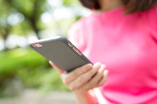 Uso della donna del telefono al parco all'aperto