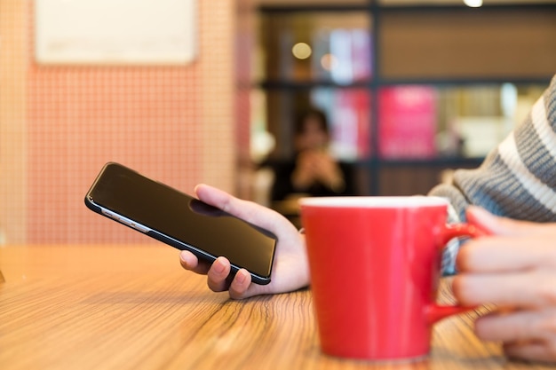 Uso della donna dello smartphone al caffè