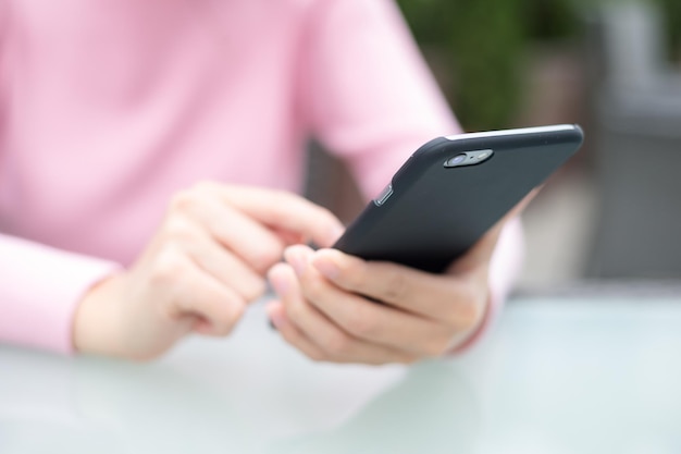 Uso della giovane donna del telefono cellulare al caffè all'aperto