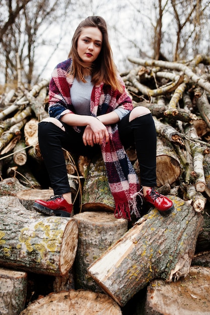 Usura giovane ragazza dei pantaloni a vita bassa sulla coperta contro i ceppi di legno su legno.