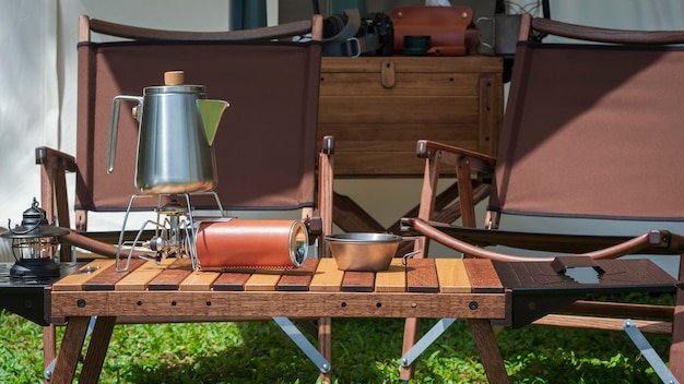 Utensili da cucina all'aperto e lanterne vintage su tavola di legno davanti alla tenda nell'area campeggio