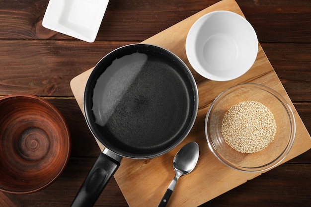 Utensili da cucina e semi di quinoa in una ciotola sul tavolo di legno