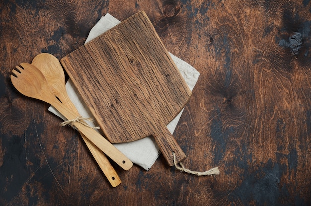 Utensili da cucina in legno. Cucchiai di legno, tagliere, tovagliolo su un vecchio tavolo di legno.