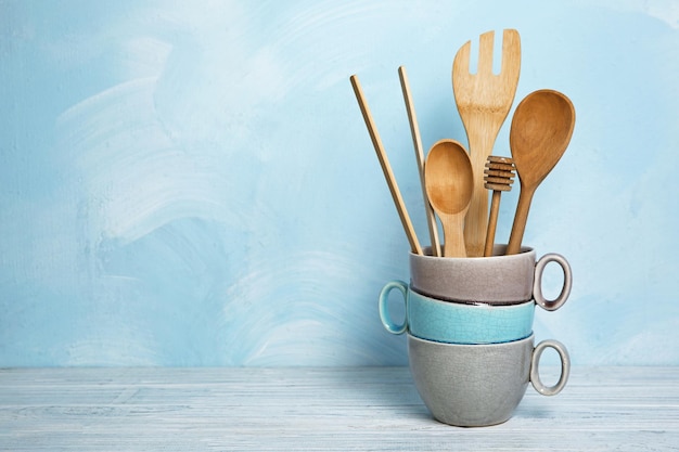 Utensili da cucina in legno in vaso sul tavolo contro la parete blu