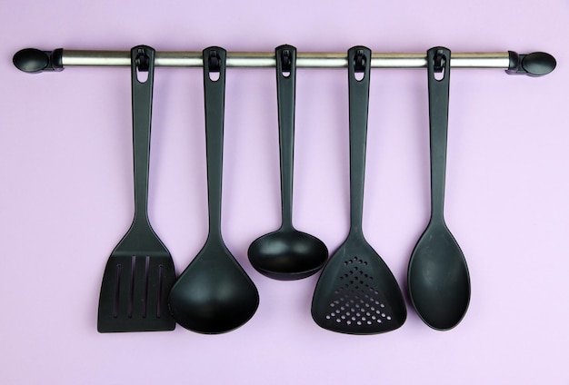 Utensili da cucina in plastica su ganci d'argento su sfondo lilac