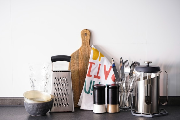 Utensili da cucina su un muro di piastrelle bianche.