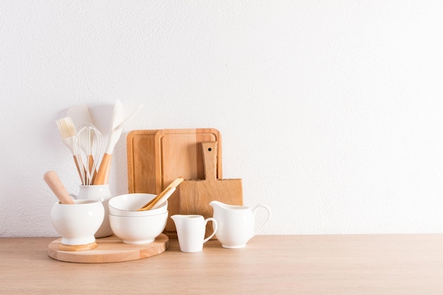 Utensili da cucina su un piano di lavoro in legno di fronte al muro bianco testurizzato una copia dello spazio per il testo