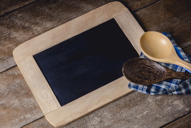 Utensili da cucina su una lavagna con un tovagliolo a quadretti blu