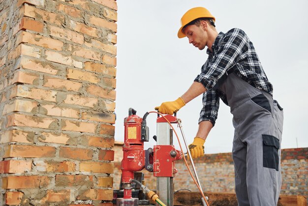 Utilizza il trapano di miscelazione Il lavoratore edile in uniforme e l'attrezzatura di sicurezza ha un lavoro nell'edilizia