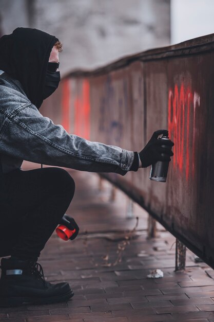 Utilizzando bomboletta di vernice spray per fare un segno di protesta. L'uomo carismatico con identità nascosta fa atti di vandalismo.