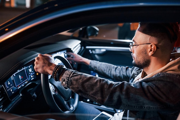 Utilizzo del display di navigazione Bell'uomo con la barba lunga in abiti alla moda che guida la sua automobile