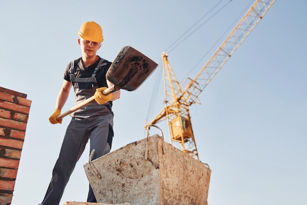 Utilizzo di showel Operaio edile in uniforme e equipaggiamento di sicurezza ha un lavoro sulla costruzione