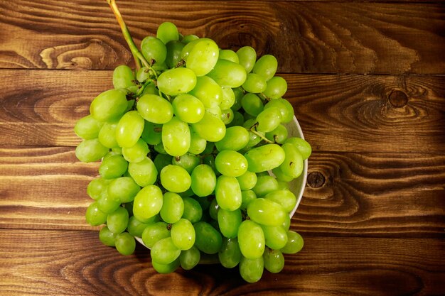 Uva bianca fresca saporita in un piatto sulla tavola di legno
