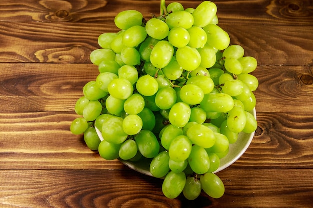 Uva bianca fresca saporita in un piatto sulla tavola di legno